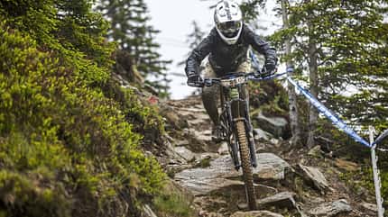 UCI EDRDH Leogang, Downhill, Mountainbike, Rennsport, 2024, Alpen, Steiniger Trail, Wettkampf, Schlamm, Fahrradtechnik Downhill-Mountainbiker mit Startnummer 25 fährt auf nassem, steinigem Trail bei UCI EDRDH Leogang 2024 durch alpines Gelände.