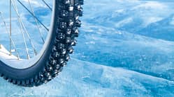 Close-up of a studded bicycle tire on the background of an icy surface. Winter sport concept. Bicycle on ice.