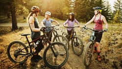 Female mountain bikers in discussion after descending mountain trail