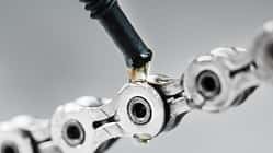 Greasing a bicycle chain with a drop of golden oil close-up on a gray background