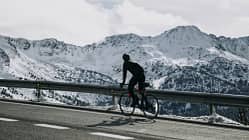 Andorra, cyclist on mountain road with snowy mountains in the background