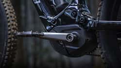 Detailaufnahme eines E-Bike-Mittelmotors mit Kurbel und Pedal, montiert an einem Mountainbike-Rahmen.