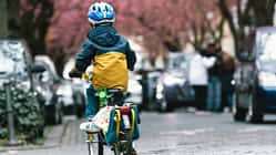 Ein kleiner Junge radelt in einer Straße.