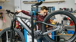 Fahrradmechaniker prüft die hintere Schaltung und die Bremsen eines Mountainbikes.