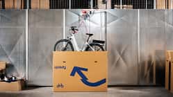 Ein Fahrrad wird aus einem Karton mit Upway-Schriftzug gehoben. 