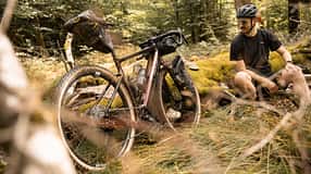 Ridley Bikes,E-Kanzo Adventure,Gravelbike,Fahrer sitzend am Baumstamm