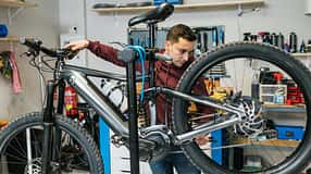 Fahrradmechaniker prüft die hintere Schaltung und die Bremsen eines Mountainbikes.