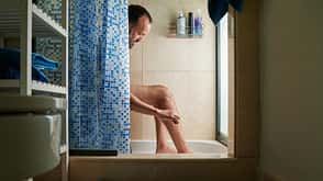 portrait of an intimate moment of a middle-aged man with beard shaving his leg in the bathroom at home portrait of an intimate moment of a middle-aged man with beard shaving his leg in the bathroom at home