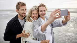 Couple and senior woman taking selfie on the beach Couple and senior woman taking selfie on the beach
