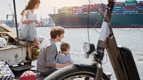 bicycle,family,transportation,vehicle,bike,people,sitting,break,tourist,helmet,relaxation,relaxed,leisure,together,Mobility,bonding,Trip,cyclist,harbour,sky,outdoor,day,watching,looking,casual clothing,arm around,container ship,togetherness,quay,pier,elbe river,riverside,resting,Bicycle tour,City Break,dock,two parents,Lens Flare,Waterfront,E-Bike,female tourist,recovering,girl,young women,mature men,three people,4-5 years,25-29 years,40-44 years,caucasian appearance,father,mother,daughter,family with one child,Hamburg,tourism,Travel,Nautical Vessel,ship,cargo vessel,cargo ship,water,River,waters edge,parents Germany, Hamburg, family having a break from a bicycle tour at River Elbe watching a container ship