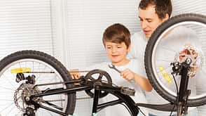 Dad teaching son repairing bicycle using spanner Dad teaching son repairing bicycle using spanner