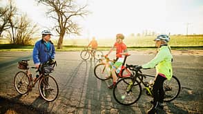 Wide shot of group of senior cyclists preparing for sunrise ride on spring morning Wide shot of group of senior cyclists preparing for sunrise ride on spring morning