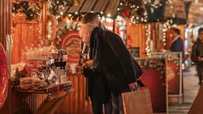 Weihnachtsmarkt, Ernährun, Zuckerwatte, Maronen, Plätzchen Zwei Personen auf dem Weihnachtsmarkt stehen an einem kleinen Stand.