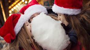 Weihnachtsmarkt, Ernährun, Zuckerwatte, Maronen, Plätzchen Drei Mädchen teilen eine Zuckerwatte. Sie haben Nikolausmützen auf.