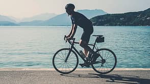 one person:CB2,bicycling:CB2,side view:CB2,male:CB2,mid-adult:CB2,outdoors:CB2,lake:CB2,Annecy:CB2,Alps:CB1,cyclist:CB3,road bicycle:CB3,lycra:CB2 Cyclist by Lake Annecy, France
