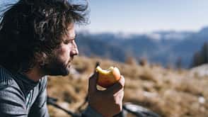 Mountain biker enjoys healthy snack in mountain meadow Mountain biker enjoys healthy snack in mountain meadow