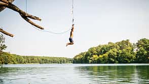 Man jumping into the lake from the swinging rope Man jumping into the lake from the swinging rope