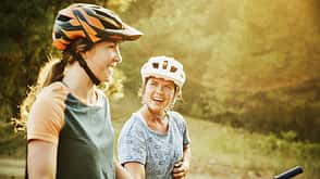 Laughing female mountain bikers in discussion while resting during ride Laughing female mountain bikers in discussion while resting during ride