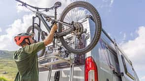 Mountain biker loads bike on camper van Mountain biker loads bike on camper van