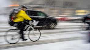Verschwommener Radfahrer in gelber Jacke auf der Straße.