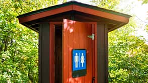 Wunderschöne rote und braune öffentliche Toilette in der Mitte des Waldes, Gatineau Park, Quebec, Kanada. Wunderschöne rote und braune öffentliche Toilette in der Mitte des Waldes, Gatineau Park, Quebec, Kanada.