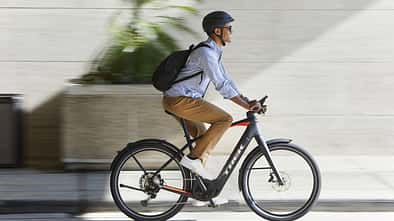 Mann mit Rucksack in der Stadt auf einem E-Bike Trek Allant+