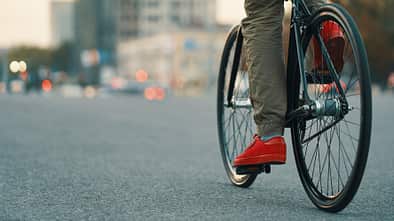 Closeup of casual man legs riding classic bike on city road
