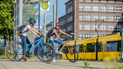 Zwei Jugendliche mit Puky Fahrrad an Bushaltestelle
