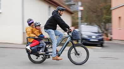 E-Lastenrad I Test Centurion Vario R960i I Mann fährt mit 2 Kindern auf dem Heck des Longtail-Lastenrad 