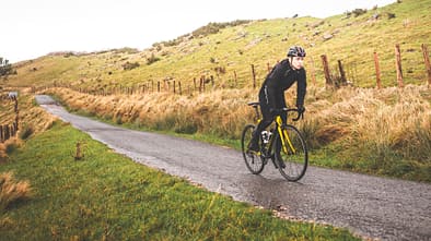 Young caucasian cyclist man climbing a hill in a foggy mountain.