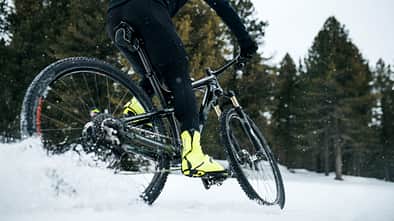 Midsection of mountain biker riding in snow outdoors in winter.