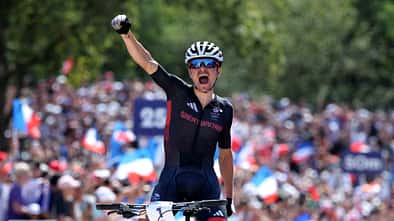 Thomas Pidcock of Team Great Britain celebrates at finish line as gold medal winner during the Men's Cross-Country on day three of the Olympic Games Paris 2024 at Elancourt Hill on July 29, 2024 in Elancourt, France. (Photo by Alex Broadway/Getty Images)