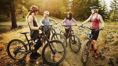 Female mountain bikers in discussion after descending mountain trail