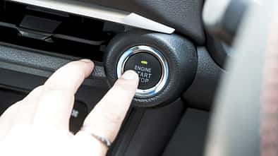 Owner finger to touching and press button function start and stop car engine in the automobile.
