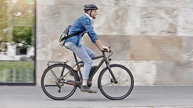 Mann pendelt mit seinem E-Bike zur Arbeit