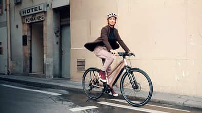 Frau fährt mit stylishem City-E-Bike von Riese und Müller durch die Stadt. E-Bike-Trends 2025.