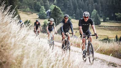 Gravelbikes,Action,vier Fahrer hintereinander,Grasbüschel
