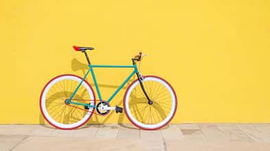 Buntes Fahrrad vor knallgelber Wand 