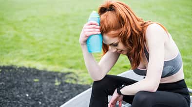 Young woman with long red hair wearing sportswear, exercising outdoors.