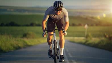 Professional cyclist sprinting on the road at sunset.