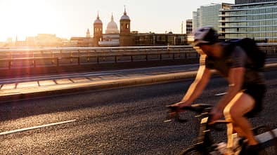 London, verschwommene Bewegung eines schnell fahrenden Radfahrers auf der London Bridge mit Blick auf die St. Paul's Cathedral im Hintergrund