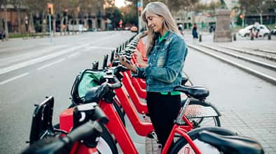Reife Frau im Urlaub und Mieten eines E-Bikes, um Barcelona zu erkunden.