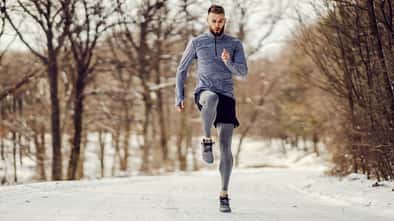 Junger Sportler läuft im Wald auf einem schneebedeckten Weg. Junger Sportler läuft im Wald auf einem schneebedeckten Weg.