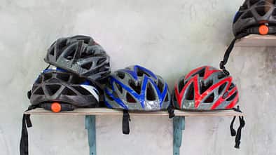 5 Helme auf einem Regal, das an der Wand hängt.