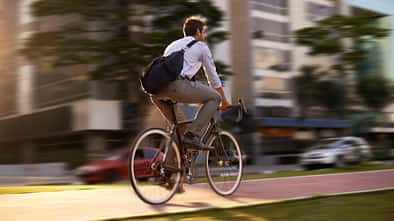 Verschwommener Fahrradfahrer mit Umhängetasche in der Stadt Verschwommener Fahrradfahrer mit Umhängetasche in der Stadt