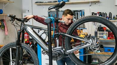 Fahrradmechaniker prüft die hintere Schaltung und die Bremsen eines Mountainbikes.