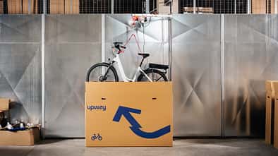 Ein Fahrrad wird aus einem Karton mit Upway-Schriftzug gehoben. 