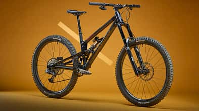 Das Bild zeigt ein Dedicated Senduro Mountainbike in Studioaufnahme vor orangem Hintergrund.