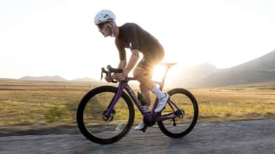 Radfahrer auf einem Pinarello F7 in der Farbe Steel Orchid mit Sonnenuntergang