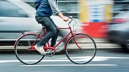 Man cycling on red bicycle in street with movement